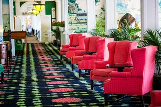 a neat row of red upholstered chairs sit atop of black and green and red patterned carpet