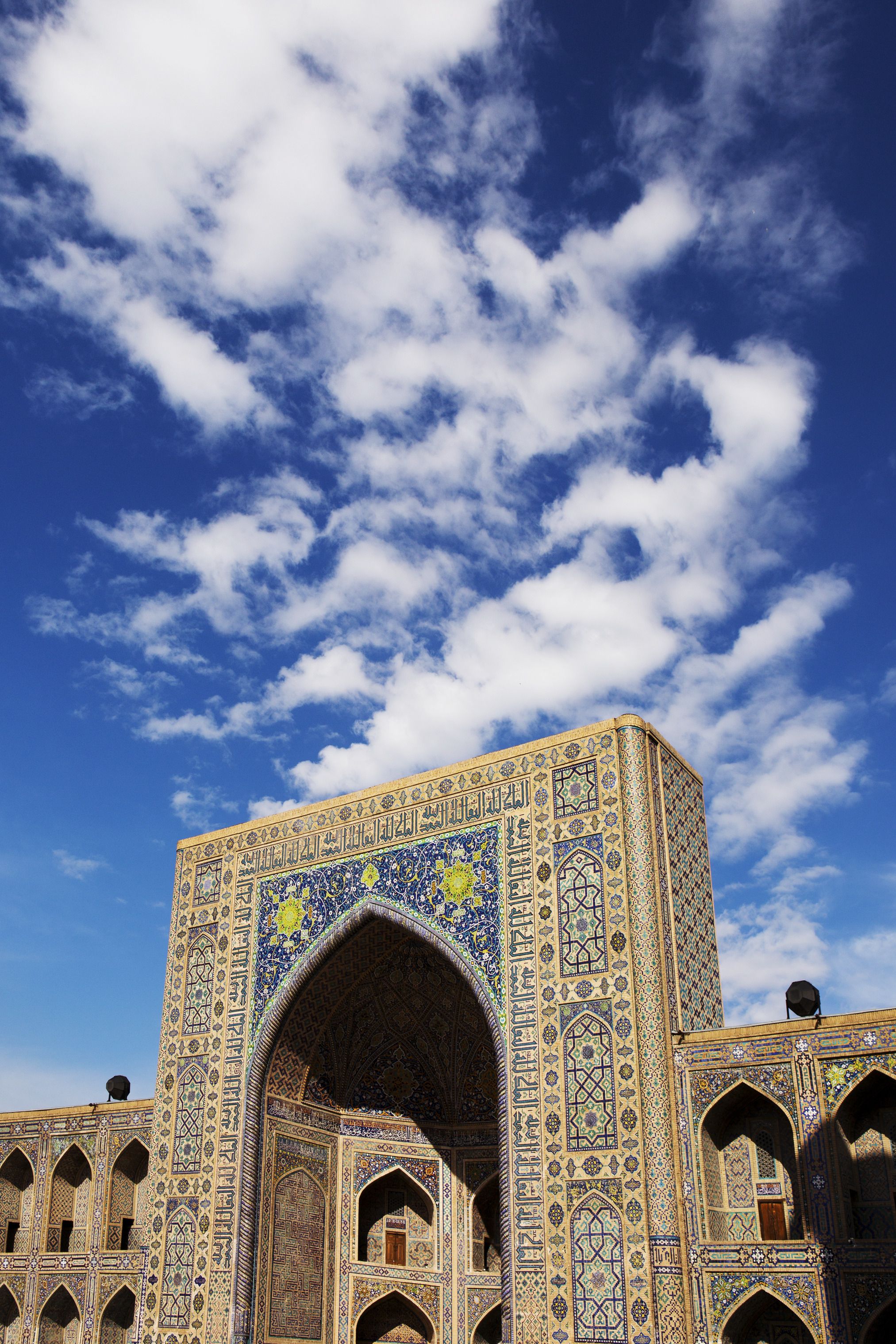 a blue and tan colored exterior of a building with intricate tilework against a vivid blue sky