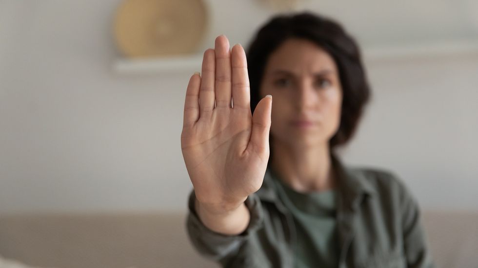 worried concerned young woman showing palm, making hand stop gesture