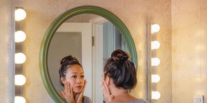 worried east asian woman checking her face skin in the mirror