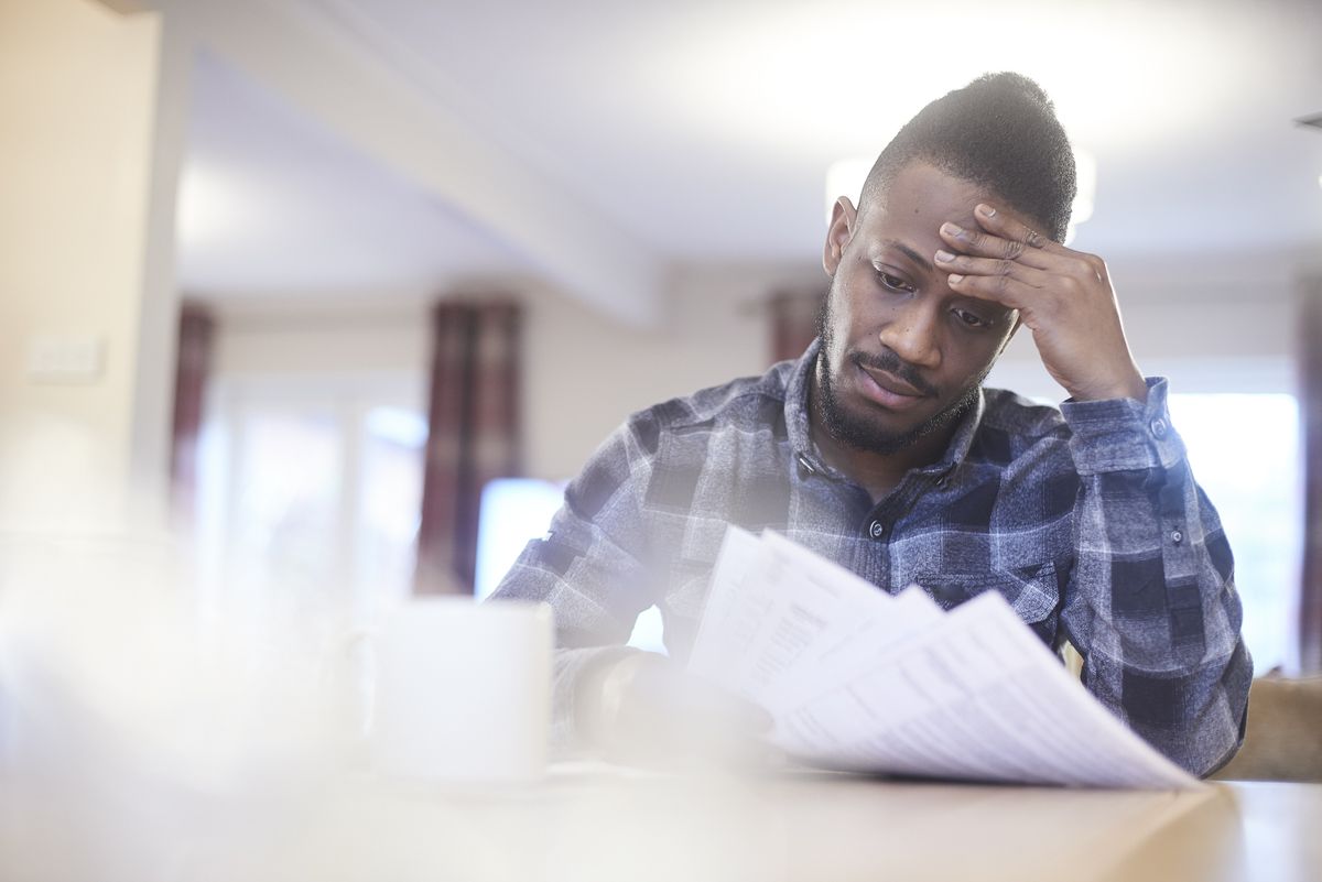 worried young male reading through household bills