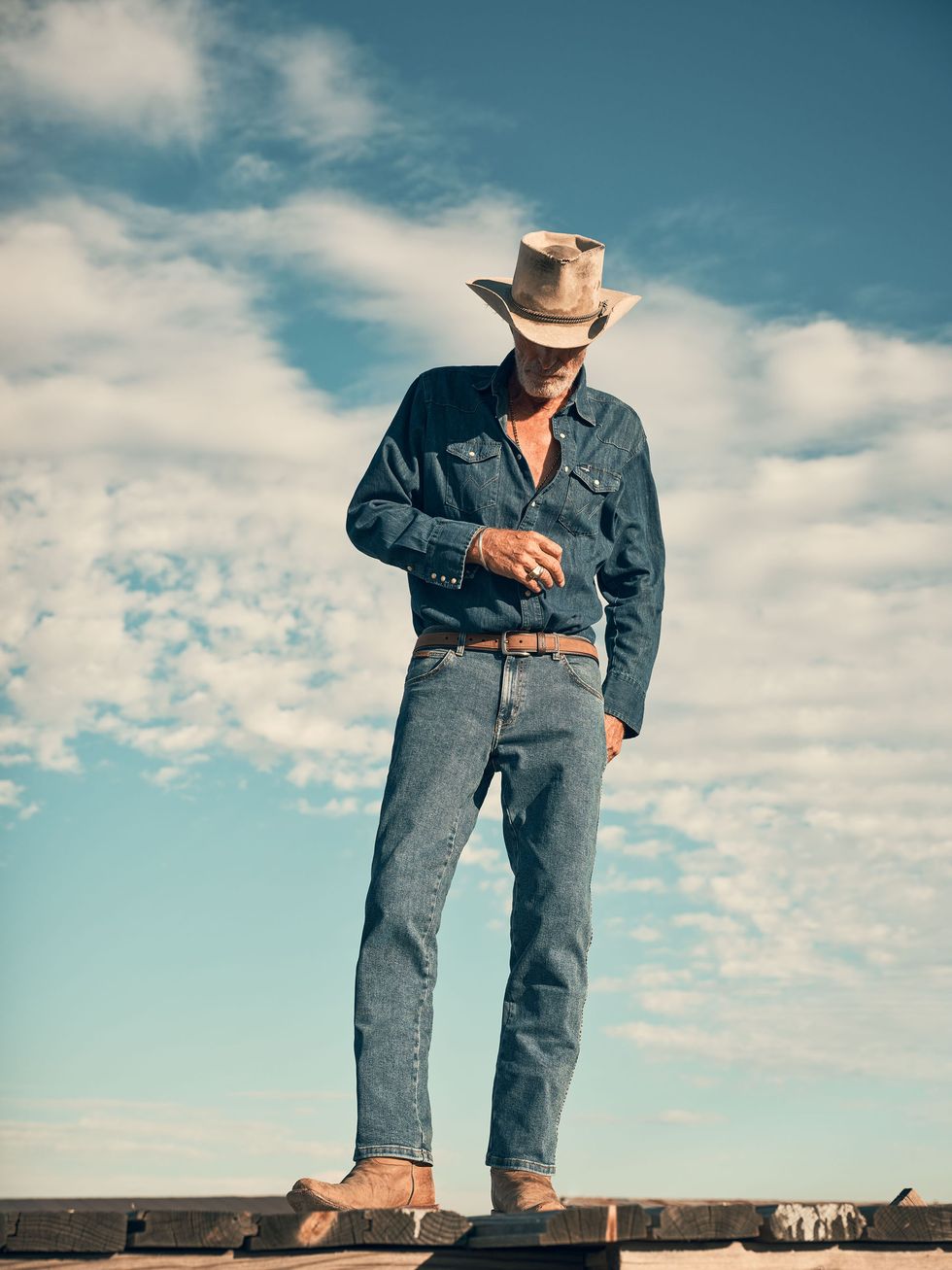 a man wearing a cowboy hat and standing on a roof