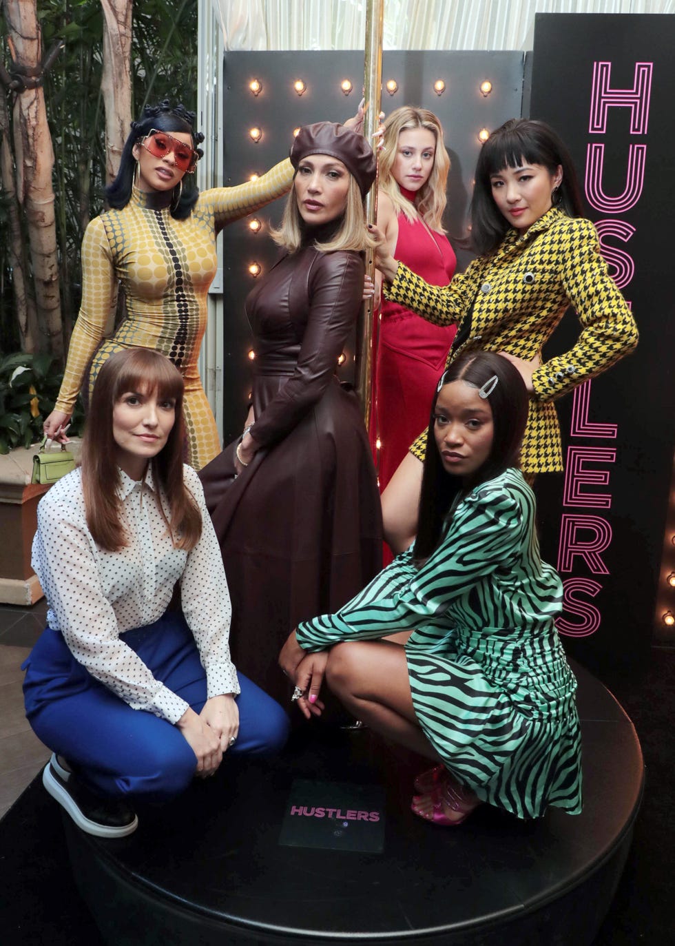 lorene scafaria, cardi b, jennifer lopez, lili reinhart, constance wu and keke palmer pose around a strip pole to promote their movie hustlers