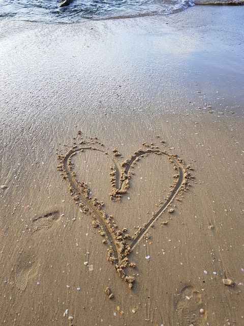 Written on the sand, heart shape at the water's edge
