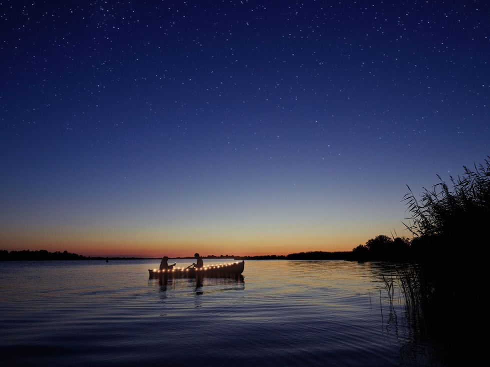 Terwijl de zonsondergang zijn gekleurde sporen aan de horizon achterlaat zie je meer en meer sterren aan de hemel boven het water verschijnen