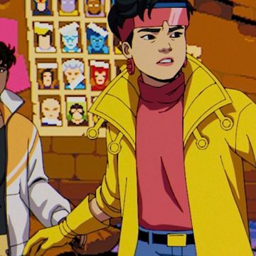 a scared man in a jacket standing behind a brave woman in a bright yellow coat and pink shirt