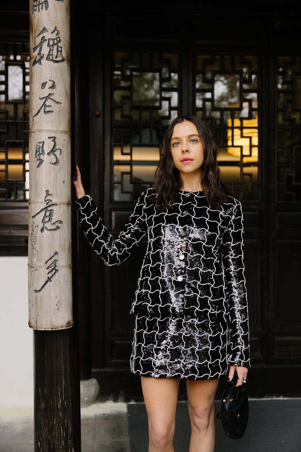 a person standing next to a decorative column while wearing a stylish outfit