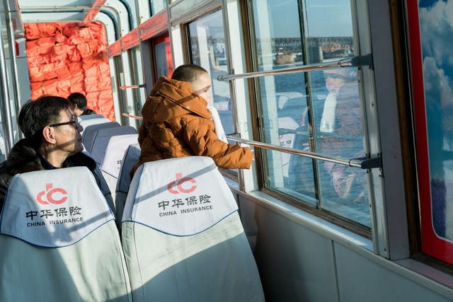 Een vader vaart met zijn zoon op een boot op de rivier de Yalu waar toeristen een blik op NoordKorea wordt gegund In tijden van verhoogde spanningen houden de boten meer afstand tot de overzijde