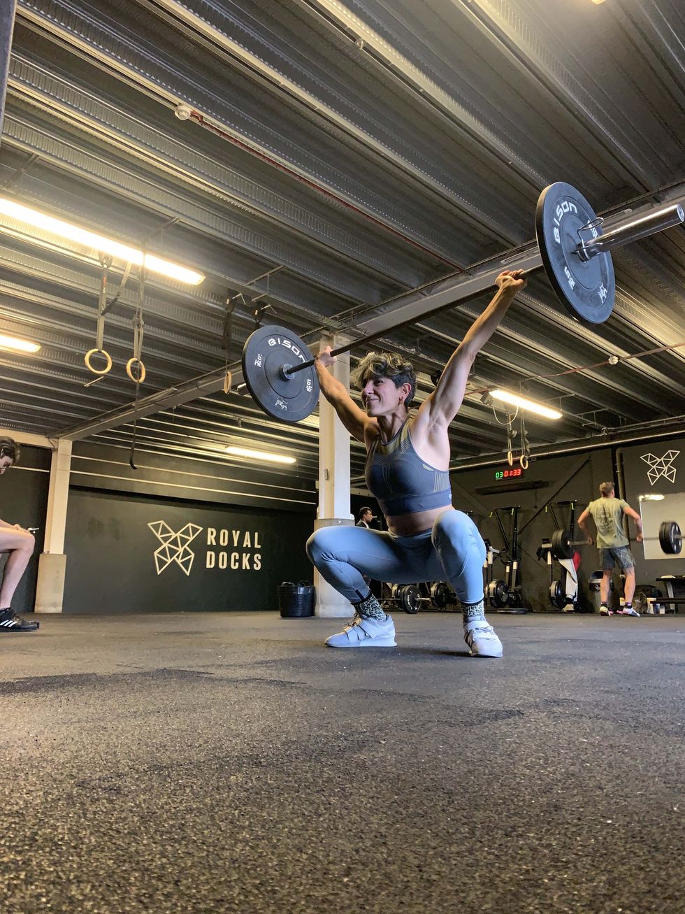 yanar holding a barbell and weights in a snatch position