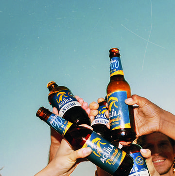 un grupo de personas brinda con cervezas el Águila