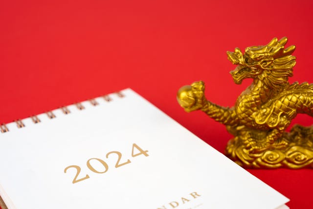 year of the dragon 2024 calendar and golden dragon toy on red background