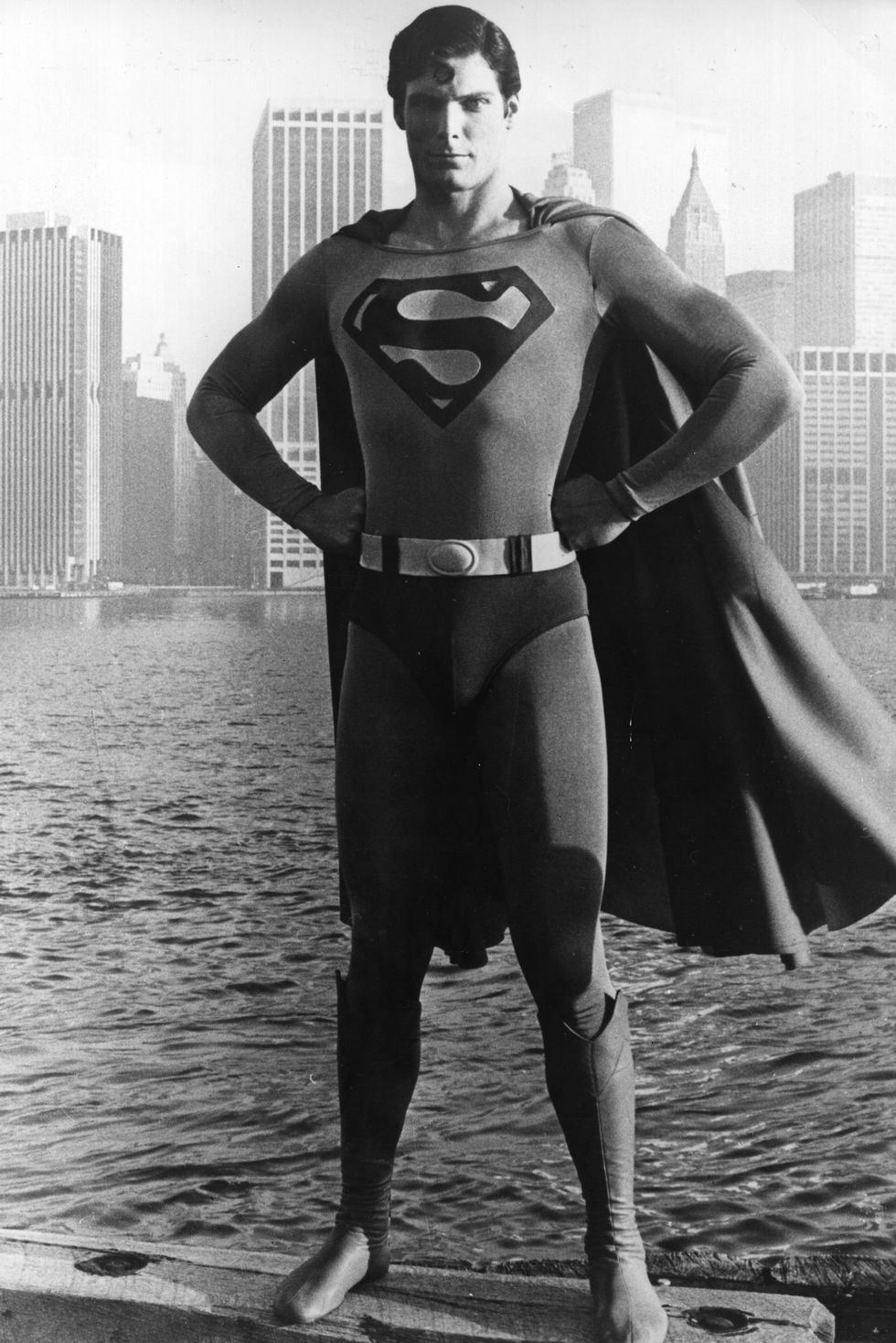 a man stands before the manhattan skyline dressed as the comic book hero superman with his arms on his hips