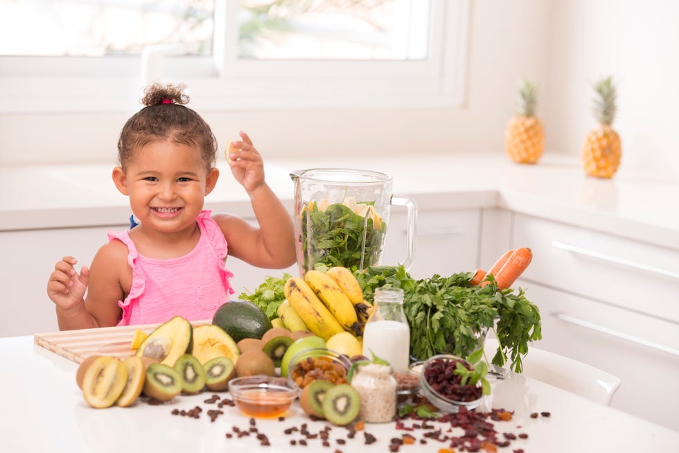 2-3 years old assistant in the kitchen. Making juices.