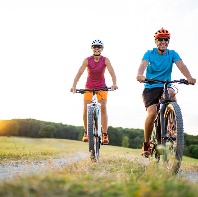 40 50 years old sporty couple cycling on electric mountain bikes in rural environment