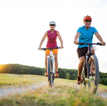40 50 years old sporty couple cycling on electric mountain bikes in rural environment