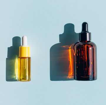 yellow and amber glass bottles with liquid on pastel light blue teal background essential oil or facial serum in vials are used for skin care procedures concept of health spa and wellbeing sunlight makes shadows and illuminating reflections from bottle