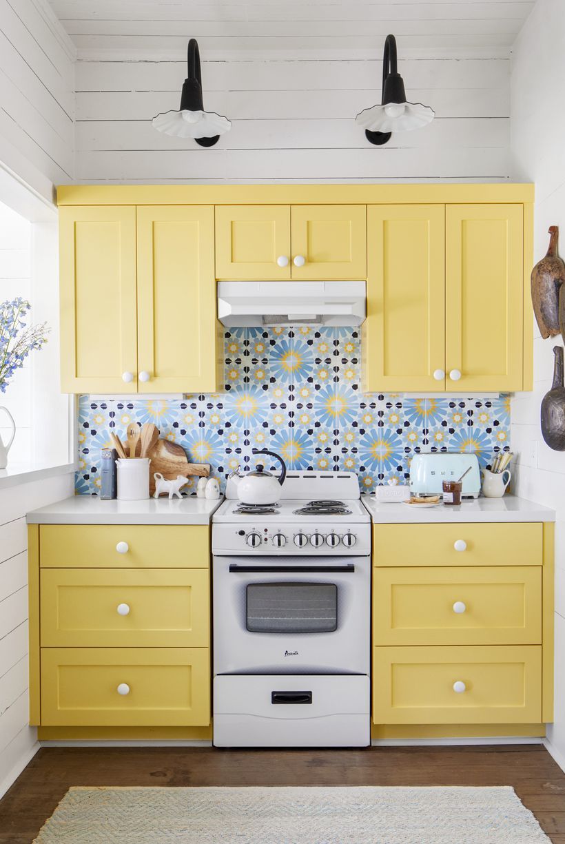small kitchen with yellow cabinets, white shiplap walls, and blue, navy, and yellow patterned tile backsplash