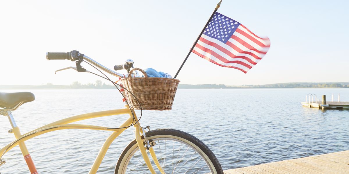 yellow beachcruiser bicycle with united states flag blowing in the wind on a jetty at an idyllic lake in summer against blue sky