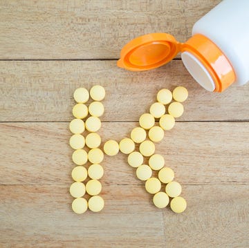 yellow pills forming shape to k alphabet on wood background