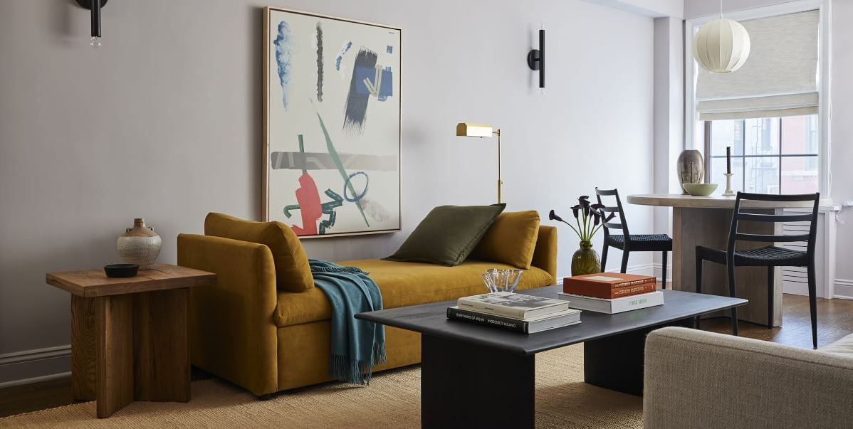 mustard color sleeper sofa in living room with art and black coffee table