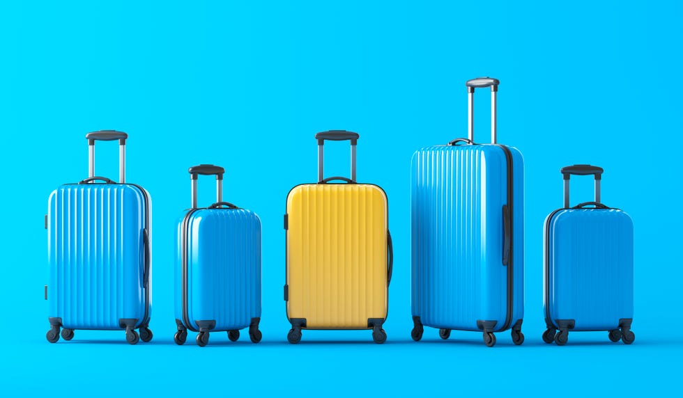 yellow suitcase standing in terminal, full of blue suitcases