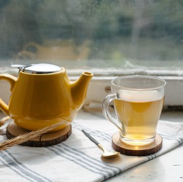 yellow teapot and glass cup with herbal tea on the window sill