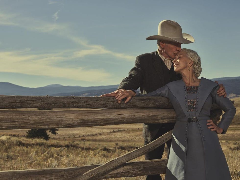 Harrison Ford and Helen Mirren share a kiss while standing in the countryside in Yellowstone, 1923