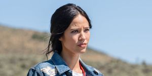 kelsey asbille in a field talking to rainwater she is wearing a long floral print skirt and jean jacket with western embroidery and  strand of long red beads