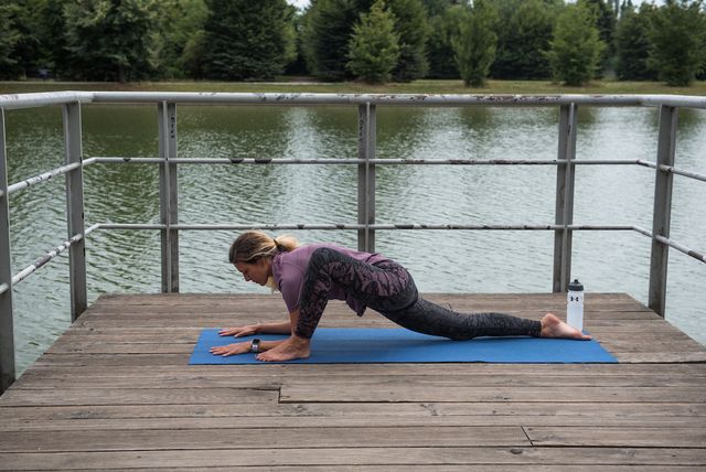 donna che fa yoga vicino a un laghetto