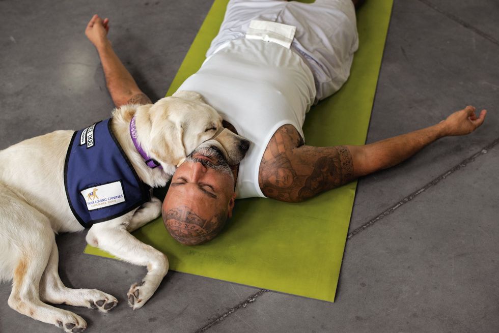 In een staatsgevangenis in de buurt van San Diego rust Patrick Acua in sawasana een houding van diepe ontspanning samen met Zeus de hulphond die hij traint De yogales wordt gegeven via de nonprofitorganisatie Prison Yoga Project Acua beoefent al meer dan twintig jaar yoga achter de tralies