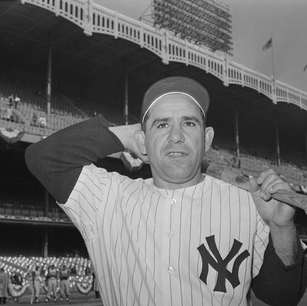 yogi berra holding his bat over his left shoulder and reaching behind his head
