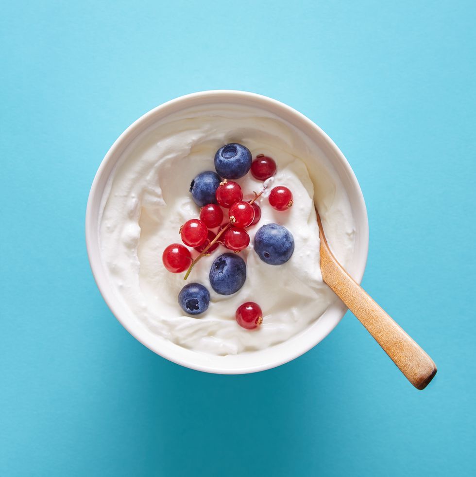 bowl with yogurt and berries on a blue background viewed from above