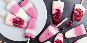 food background  homemade berry yogurt ice pops with frozen black currant and blood orange slices  on rustic gray table, high angle view