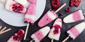 food background  homemade berry yogurt ice pops with frozen black currant and blood orange slices  on rustic gray table, high angle view