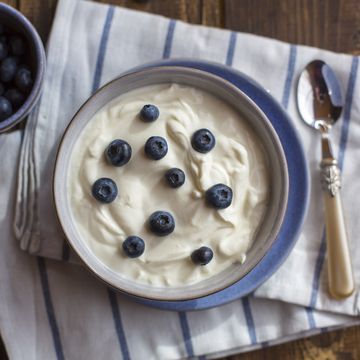 yogurt with blueberries in bowl on wood