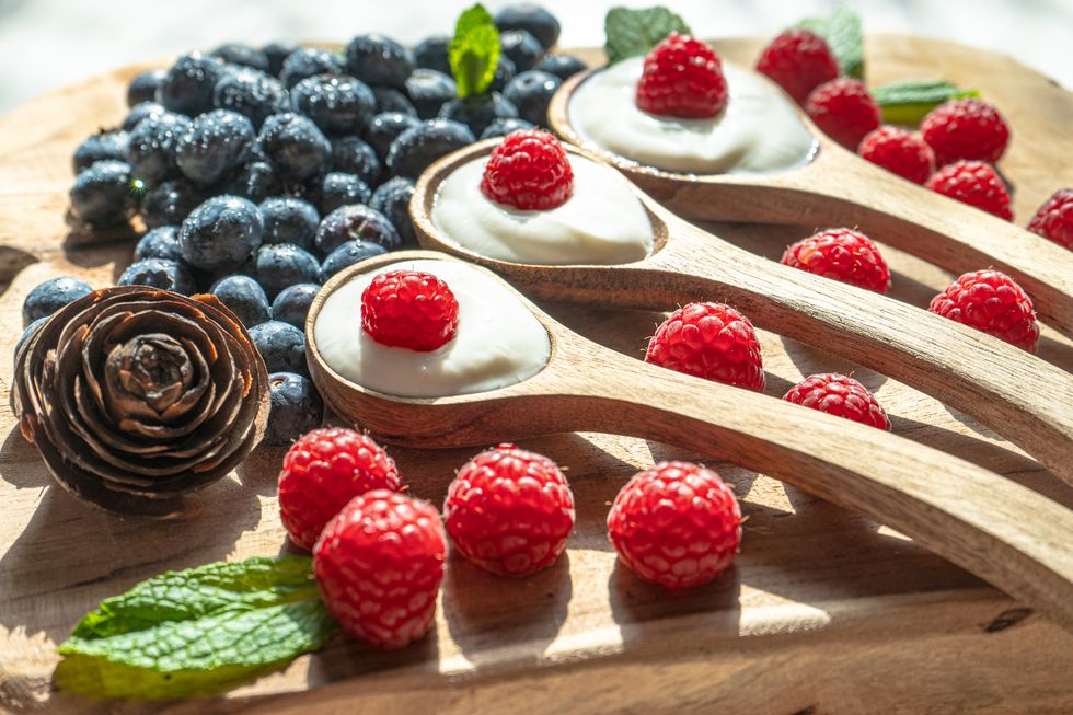 yogurt with spoons,healthy breakfast with fresh greek yogurt, muesli and berries on background