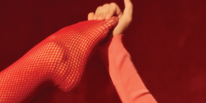 woman wearing red fishnet stockings grabbing her foot
