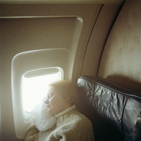 youg woman sleeping on airplane, sunrise