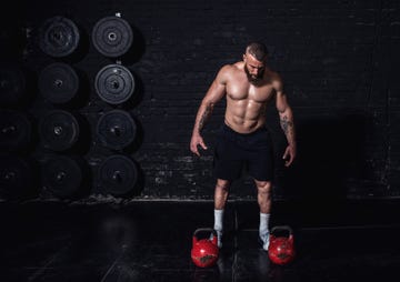 young active sweaty strong muscular fit man with big muscles preparing and concentrating for heavy kettlebell hardcore cross workout training in the gym real people exercising