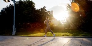 young active woman running in city park in morning light