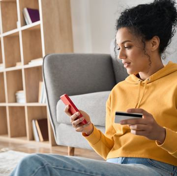 young adult african american girl sitting indoors doing mobile payment online