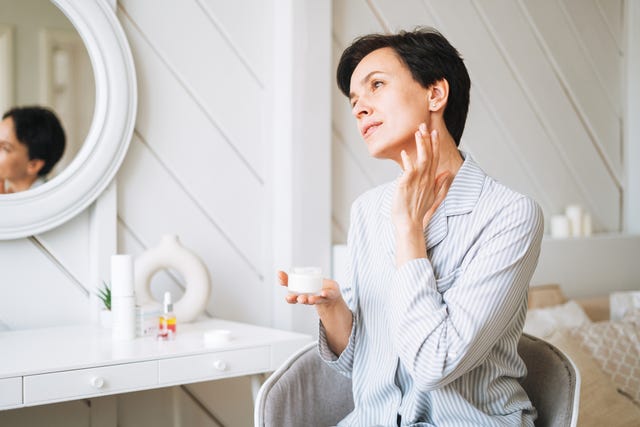 una mujer de 40 anos se aplica crema en la cara