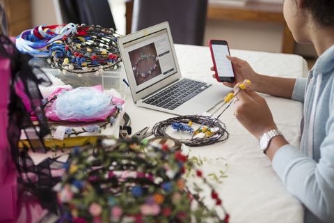 young adult female entrepreneur making accessories and checking online sales