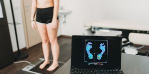young adult woman is standing on a medical pressure scanner to analyze her footprint and realize new shoe insoles to improve her posture