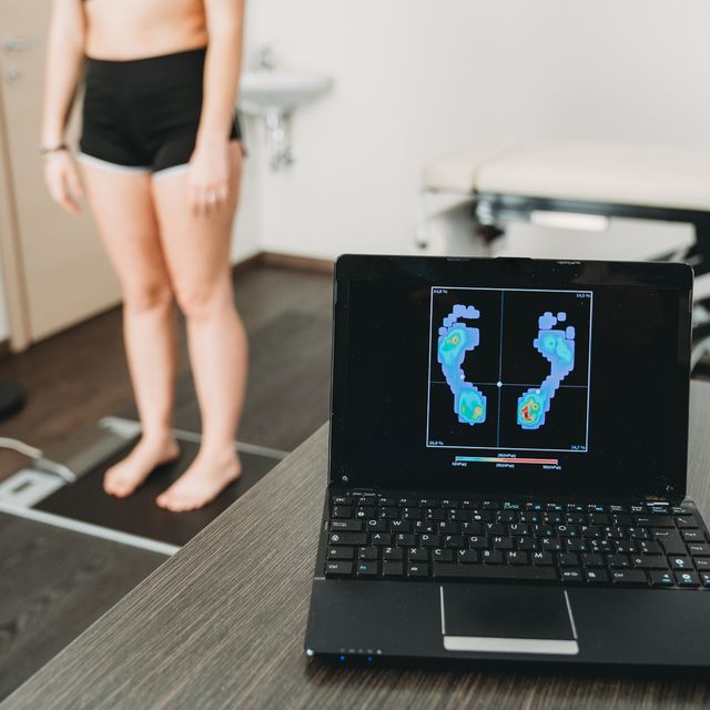 young adult woman is standing on a medical pressure scanner to analyze her footprint and realize new shoe insoles to improve her posture