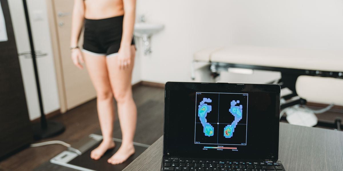 young adult woman is standing on a medical pressure scanner to analyze her footprint and realize new shoe insoles to improve her posture