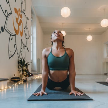 young adult woman practicing yoga at the yoga studio doing sun salutation pose