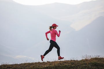 young adult woman running in mountains at sunset