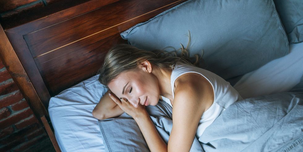 young adult woman with blonde long hair sleeping on bed in loft room at home