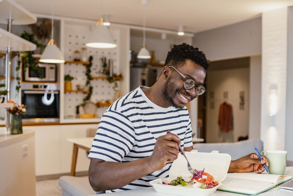 young african american man eating takeaway meal at home and planning activities